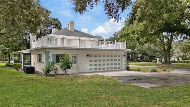 exterior space featuring central AC unit, a balcony, a garage, and a lawn