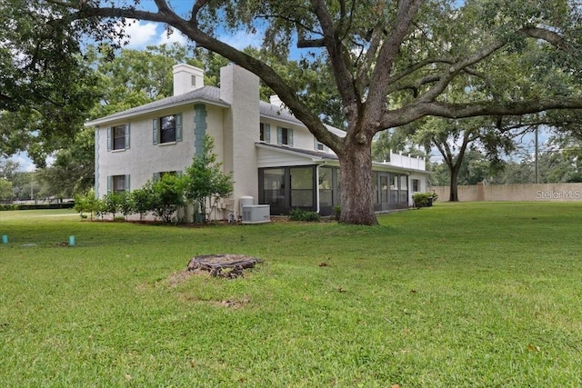 back of house with a sunroom and a lawn