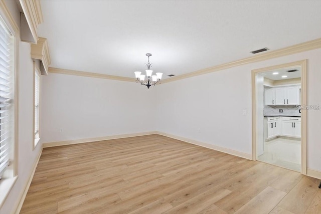 unfurnished room with a notable chandelier, ornamental molding, and light hardwood / wood-style floors