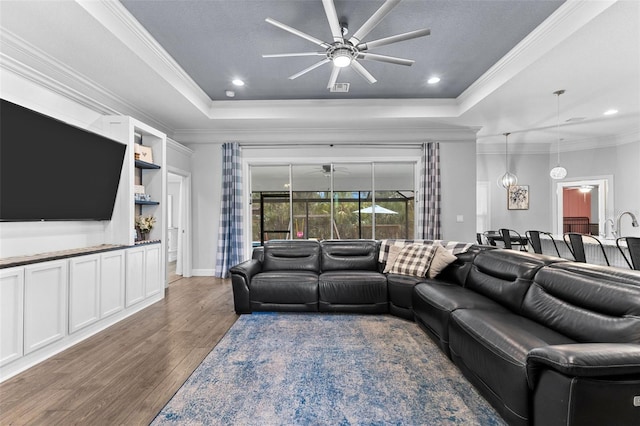 living room featuring ceiling fan, crown molding, dark hardwood / wood-style floors, and a raised ceiling