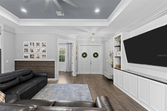 living room with ceiling fan, dark wood-type flooring, crown molding, and a tray ceiling