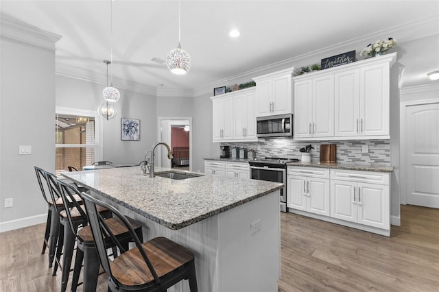 kitchen with pendant lighting, sink, stainless steel appliances, white cabinets, and light stone counters