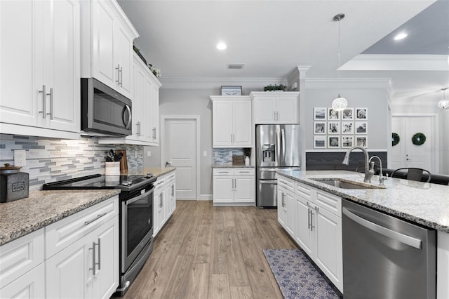 kitchen with sink, hanging light fixtures, white cabinets, and stainless steel appliances