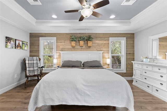 bedroom with ceiling fan, wood walls, and a raised ceiling