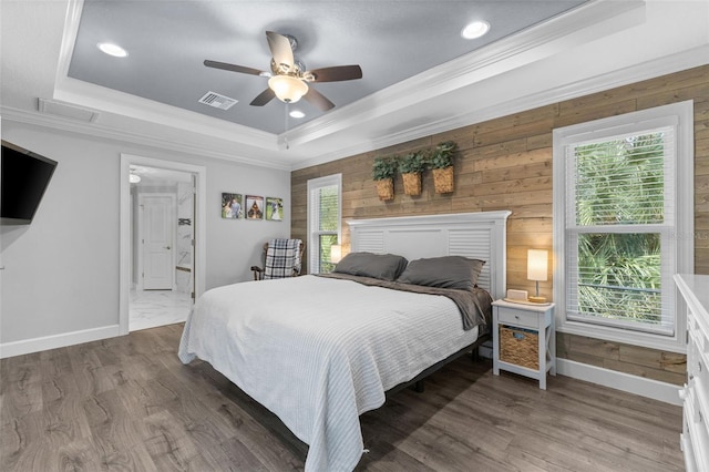 bedroom with ceiling fan, wood walls, a raised ceiling, crown molding, and dark hardwood / wood-style flooring