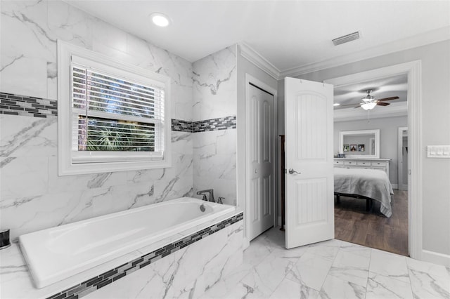 bathroom featuring ceiling fan, ornamental molding, and a relaxing tiled tub