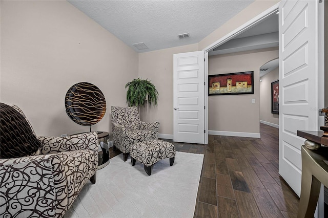 sitting room with a textured ceiling and dark hardwood / wood-style flooring