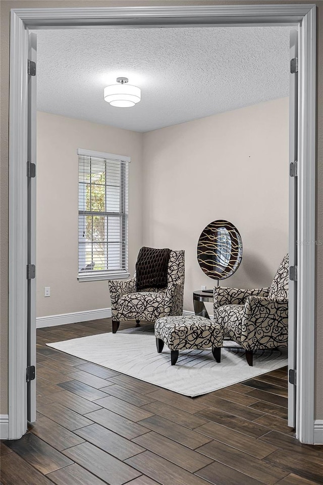 sitting room with dark wood-type flooring and a textured ceiling