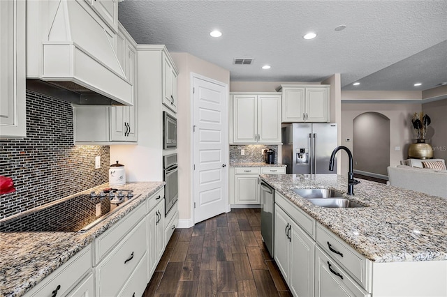 kitchen featuring premium range hood, white cabinetry, stainless steel appliances, a kitchen island with sink, and sink