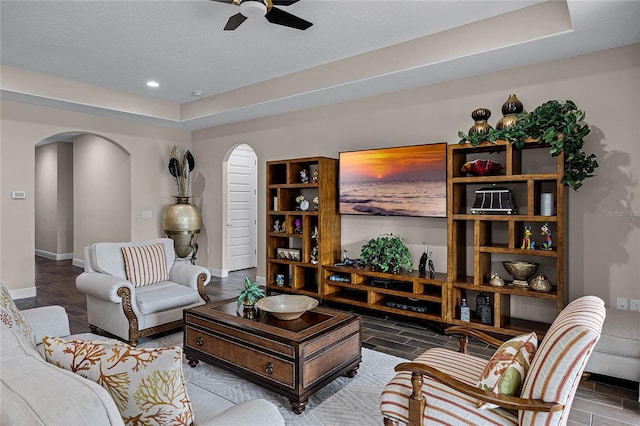 living room with ceiling fan and a raised ceiling