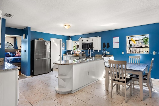 kitchen with stone counters, a sink, visible vents, freestanding refrigerator, and open shelves