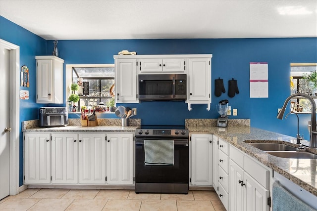 kitchen featuring appliances with stainless steel finishes, white cabinetry, a sink, and light tile patterned floors