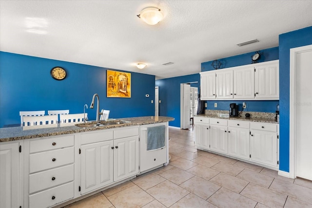 kitchen with white cabinetry, white dishwasher, visible vents, and a sink