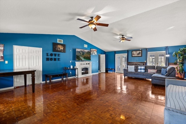 living room with a textured ceiling, a fireplace, visible vents, a ceiling fan, and vaulted ceiling