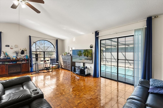 living area with vaulted ceiling, a textured ceiling, and a ceiling fan