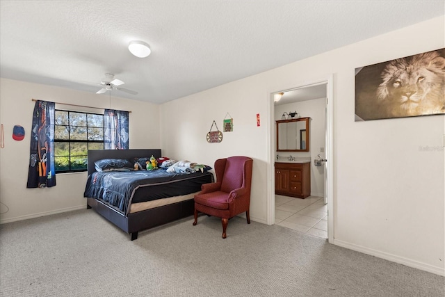 carpeted bedroom with a ceiling fan, ensuite bath, baseboards, and a textured ceiling