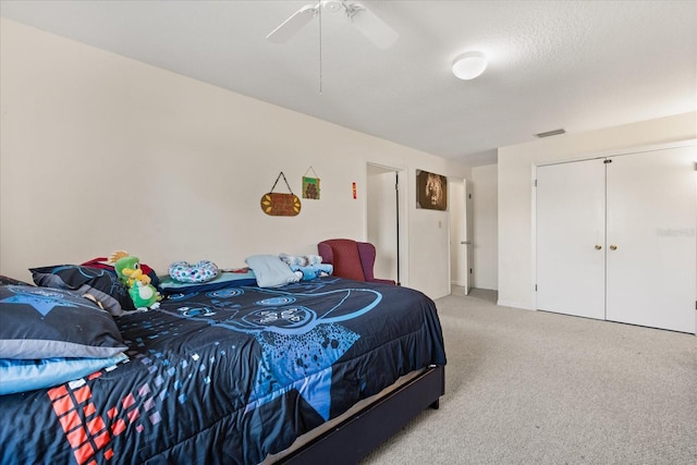 bedroom featuring a ceiling fan, light colored carpet, visible vents, and a textured ceiling