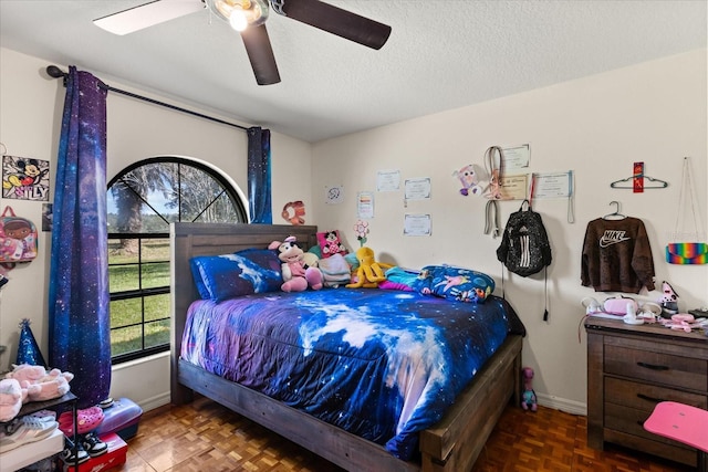 bedroom featuring a textured ceiling, ceiling fan, and baseboards