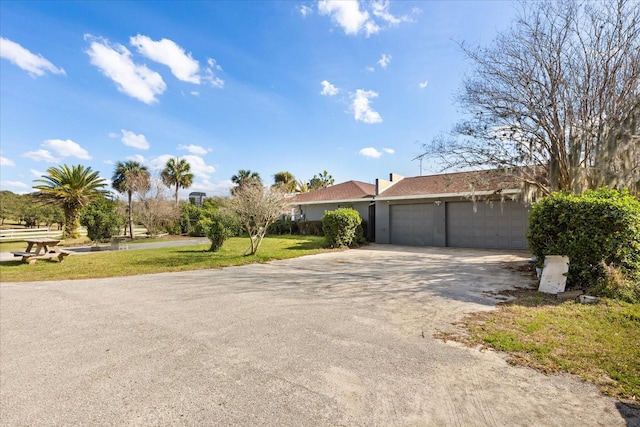 ranch-style house with a garage, driveway, and a front lawn