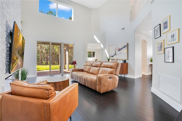 living room featuring a high ceiling, plenty of natural light, and dark hardwood / wood-style flooring