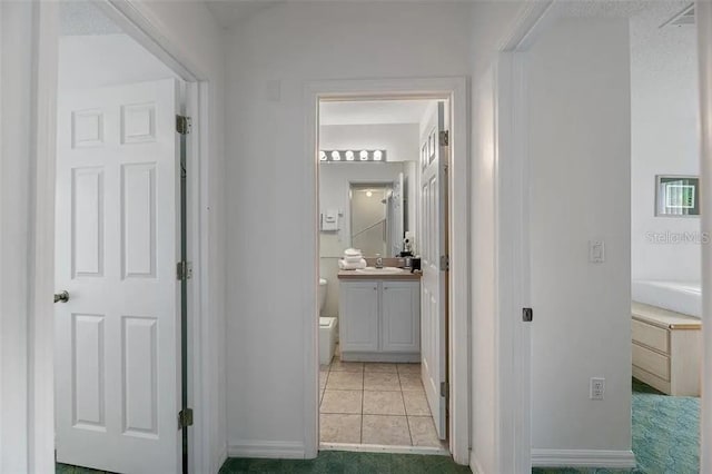 hall featuring sink and light tile patterned floors