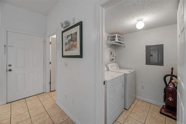 washroom with washer and clothes dryer, light tile patterned floors, a textured ceiling, and electric panel