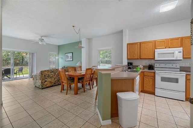 kitchen with light tile patterned floors, kitchen peninsula, sink, and white appliances