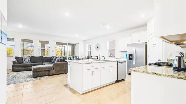 kitchen featuring appliances with stainless steel finishes, sink, white cabinetry, light stone countertops, and a kitchen island