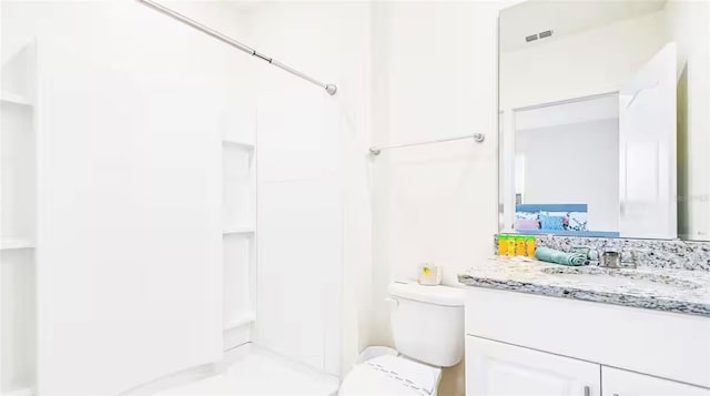 bathroom featuring vanity, toilet, and a shower