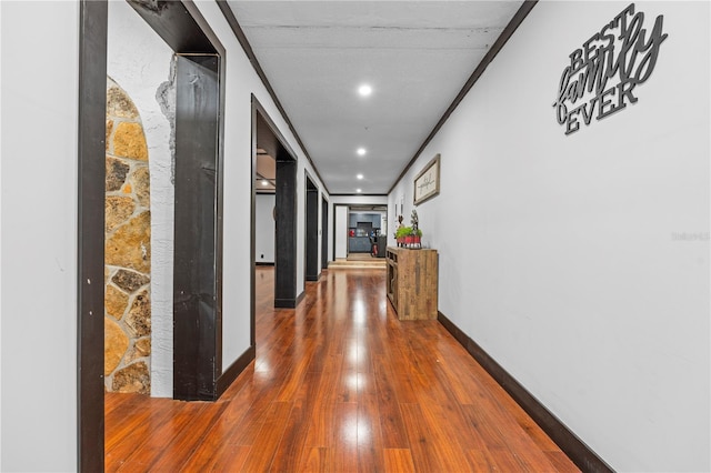 hallway with wood-type flooring and crown molding