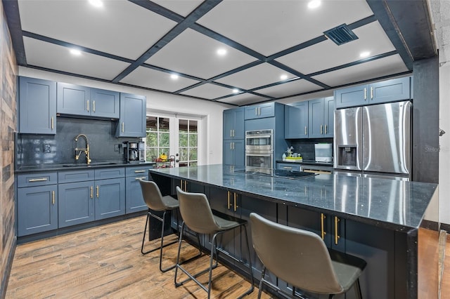 kitchen featuring a large island, sink, tasteful backsplash, a breakfast bar, and stainless steel appliances