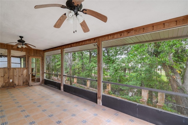 unfurnished sunroom featuring ceiling fan and a healthy amount of sunlight