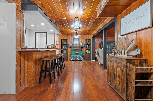 bar featuring a wood stove, hanging light fixtures, wood walls, hardwood / wood-style flooring, and wooden ceiling