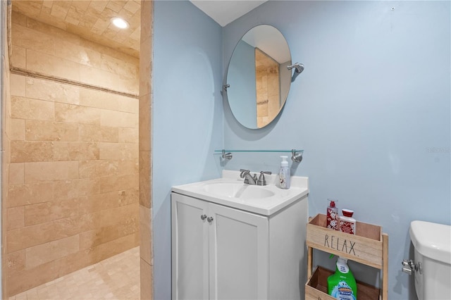 bathroom with toilet, vanity, and a tile shower