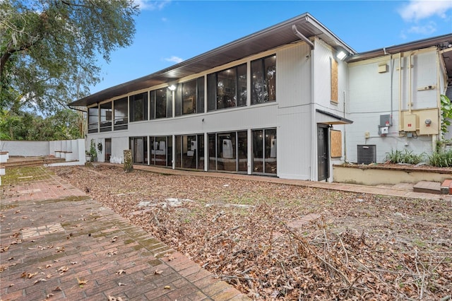 rear view of house featuring a sunroom and central AC