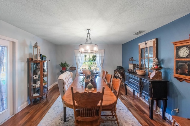 dining room featuring a notable chandelier, a textured ceiling, and dark hardwood / wood-style floors