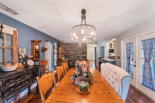 dining space with a textured ceiling, an inviting chandelier, and hardwood / wood-style floors