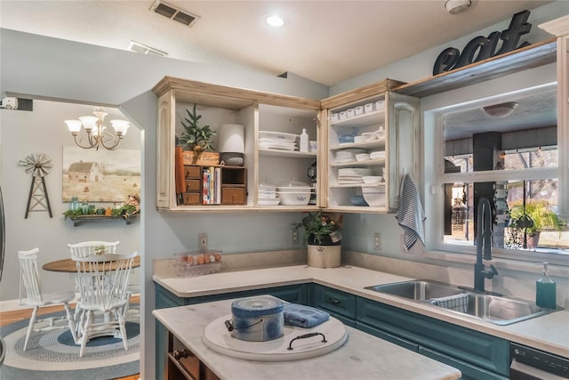 kitchen with lofted ceiling, sink, black dishwasher, blue cabinets, and a chandelier