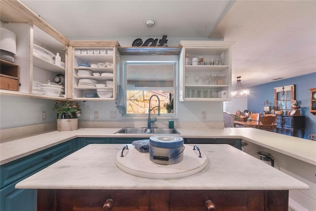 kitchen with an inviting chandelier, blue cabinetry, sink, pendant lighting, and a center island