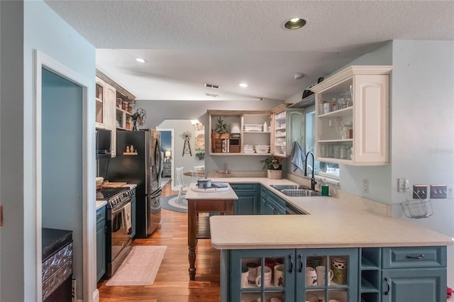 kitchen with white cabinets, stainless steel range oven, sink, kitchen peninsula, and light hardwood / wood-style flooring