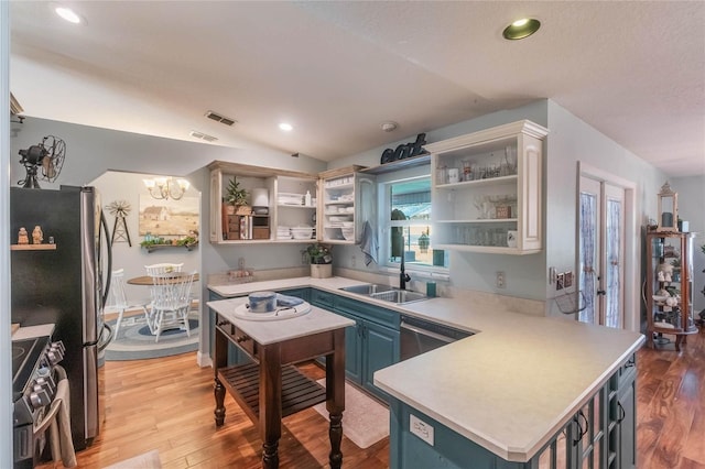 kitchen with appliances with stainless steel finishes, lofted ceiling, blue cabinets, a chandelier, and sink