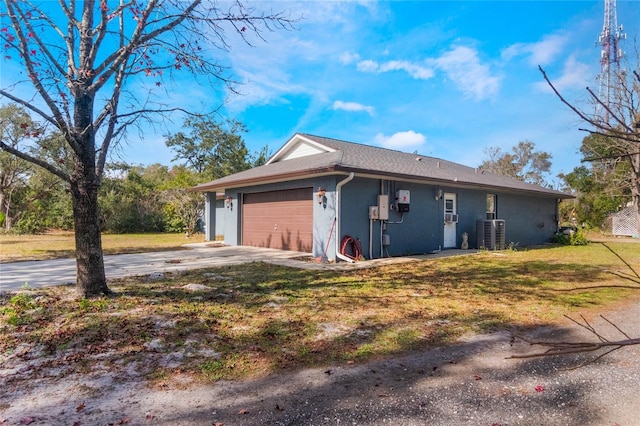 view of side of home with a lawn, cooling unit, and a garage