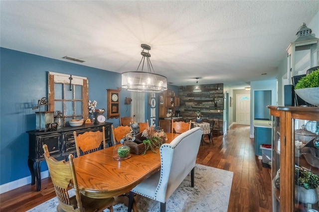 dining room with dark hardwood / wood-style floors, an inviting chandelier, and a textured ceiling