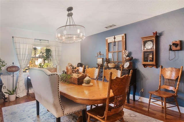 dining space with dark hardwood / wood-style flooring and a notable chandelier