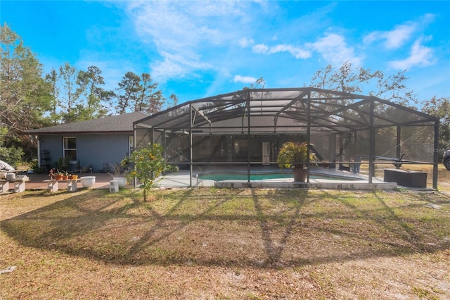 rear view of house featuring a yard, a patio, and glass enclosure