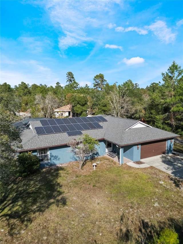 back of house with a lawn, solar panels, and a garage