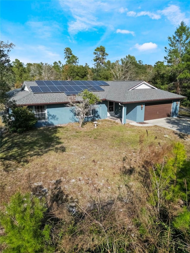 rear view of property with a yard, solar panels, and a garage