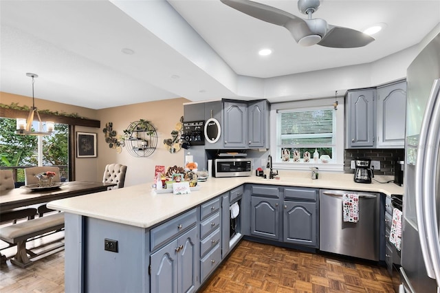 kitchen with kitchen peninsula, ceiling fan, stainless steel appliances, decorative backsplash, and hanging light fixtures