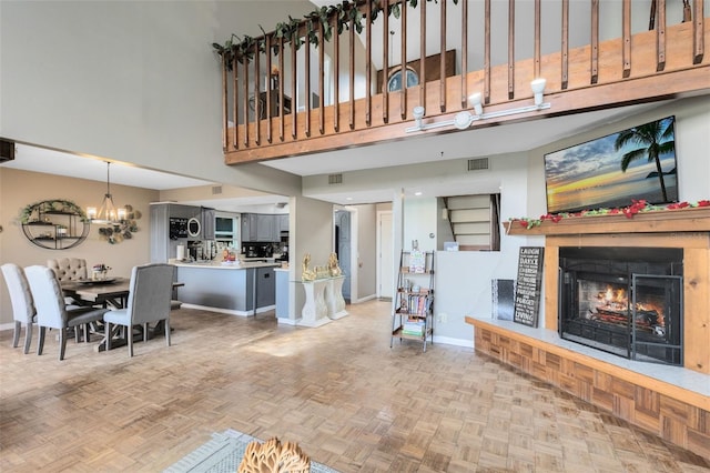 living room featuring light parquet flooring, a high ceiling, and a notable chandelier