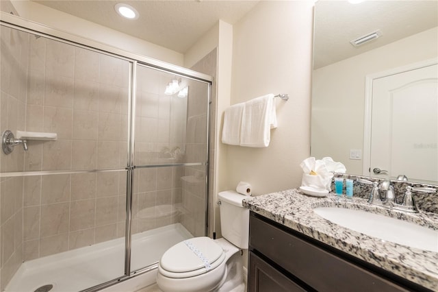 bathroom with a shower with shower door, toilet, and vanity